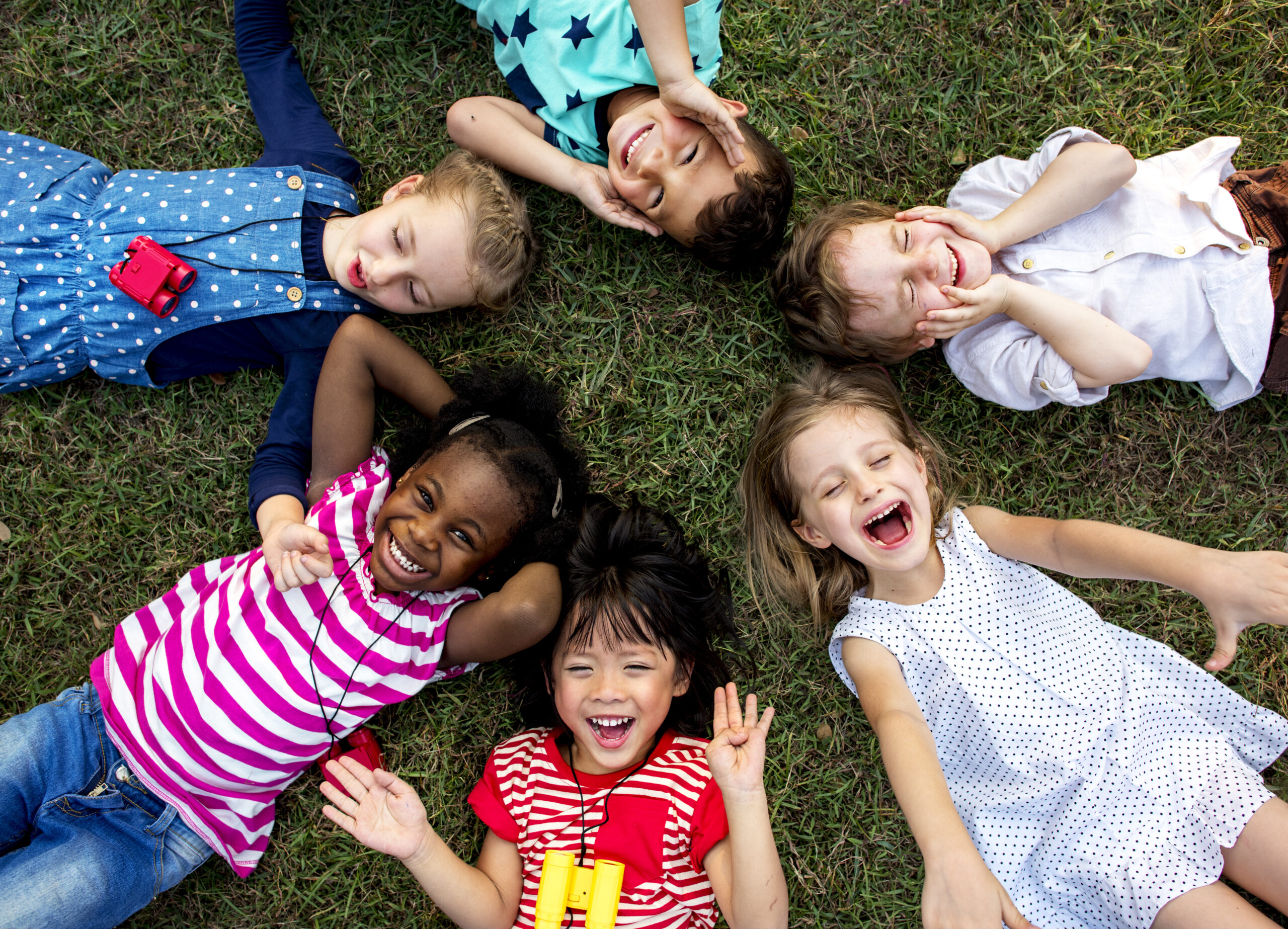 Group of kindergarten kids lying on the grass at park and relax with smiling
